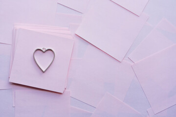 un dije de corazón de metal sobre papelitos de color rosado para san valentín y día del amor y...