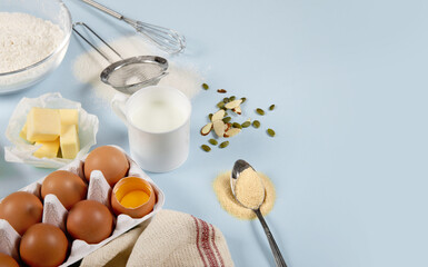 Fototapeta na wymiar Composition of ingredients for baking on colored paper (eggs, flour, butter, nuts, milk and tools)