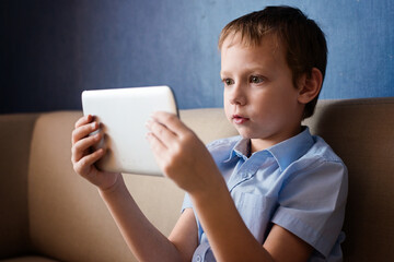 The boy watches cartoons on the tablet, the child uses technology
