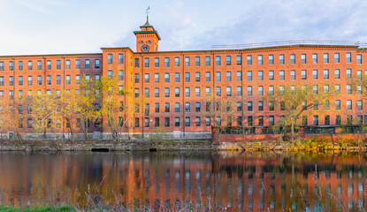 A heritage cotton mill building with a clock tower in the old industrial park of Nashua. Nowadays it is apartments on the site of Nashua river. New Hampshire, USA