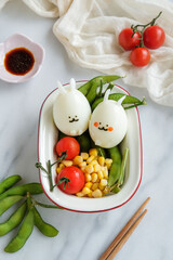 Homemade festive meals. Easter Eggs with Cherry Tomatoes, Edamame and Sweet Corn. After egg hunt, food party begins with crafted eggs decorated with healthy snacks, ideal for children.

