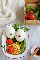 Homemade festive meals. Easter Eggs with Cherry Tomatoes, Edamame and Sweet Corn. After egg hunt, food party begins with crafted eggs decorated with healthy snacks, ideal for children.
