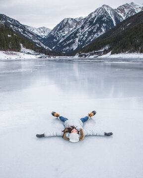 Woman laying on a frozen lake in Montana during the winter in mountains