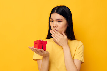 woman holding a gift box in his hands posing yellow background unaltered