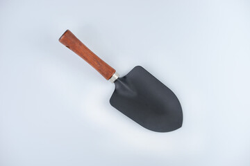 A black shovel with wooden handle on white background.