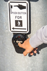 Male hand pressing a button at traffic lights on pedestrian crossing.