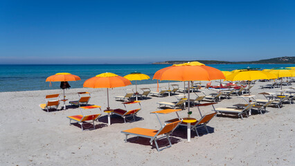 Orange and yellow beach umbrellas. Blue sky. Relaxing context. Summer holidays at the sea. General contest and location