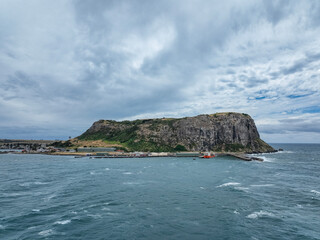 Fototapeta na wymiar High angle aerial drone view of landmark the Nut, an extinct volcano table mountain, the harbour and the town of Stanley on the north-west coast of Tasmania, Australia on a stormy day with high waves.