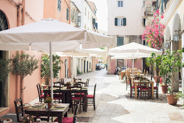 Obraz na płótnie Canvas Corfu town beautiful street with cafe and flowers, Corfu island, Ionian islands, Greece. Picturesque landmark of Kerkyra old town.