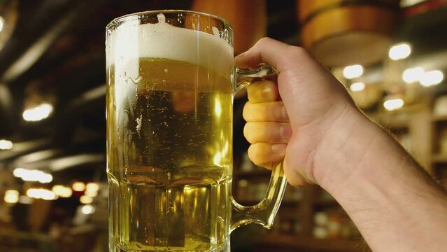 Drunk man holding full glass of beer and walking at the restaurant or pub . Waiter walking and serving big cup of draft beer .  Camera shoot from the face . Angle from the eye . Beer party concept .
