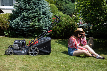 A girl is lying on the lawn resting after mowing the grass.
