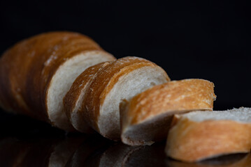 Sliced fresh french baguette on dark background.