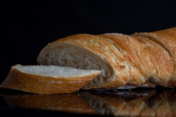 Sliced fresh french baguette on dark background.
