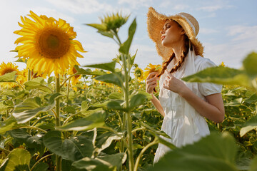 woman portrait in a hat on a field of sunflowers landscape