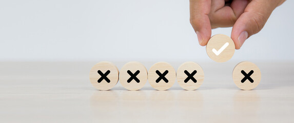 Hand choose check mark on wooden toy stack with cross symbol for true or false changing mindset or...