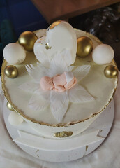 A festively decorated cake in honor of the birth of a baby in the form of a decor for a newborn baby on a lily flower