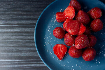 Strawberries on a plate with dark background. Strawberries on a plate with a sprinkle of sugar.