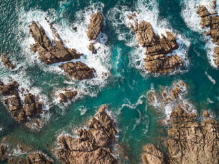 Aerial top view of sea waves hitting rocks on the beach