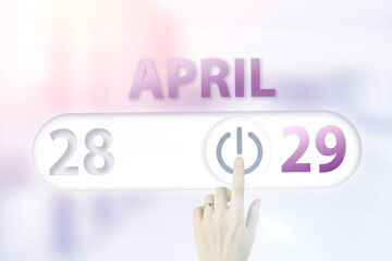 April 29th. Day 29 of month, Calendar date.Hand finger switches pointing calendar date on sunlight office background. Spring month, day of the year concept.