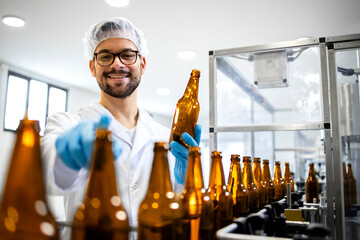 Portrait of professional experienced technologist worker standing in beer bottling factory checking...