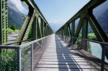 Fototapeta na wymiar Hiking on the Swiss Alp Mountains. Metal girder bridge with pathway.