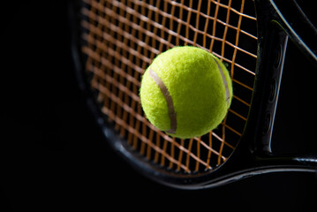 closeup tennis ball with racket on black background 