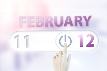 February 12nd. Day 12 of month, Calendar date.Hand finger switches pointing calendar date on sunlight office background. Winter month, day of the year concept.
