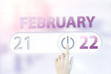 Fototapeta premium February 22nd. Day 22 of month, Calendar date.Hand finger switches pointing calendar date on sunlight office background. Winter month, day of the year concept.