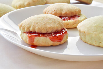 Scones with strawberry jam on a white plate. 