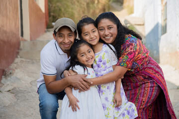 Portrait of a Latin family hugging in rural area - Happy Hispanic family in the village - obrazy, fototapety, plakaty