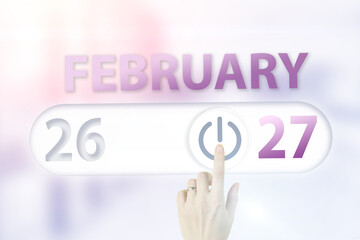 February 27th. Day 27 of month, Calendar date.Hand finger switches pointing calendar date on sunlight office background. Winter month, day of the year concept.