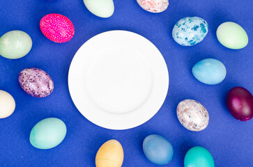Festive Easter table setting with painted eggs on blue background. Space for text. Studio Photo