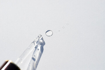 Pipette close-up with drops on the surface on a light background in soft focus. Beautiful shadow in...