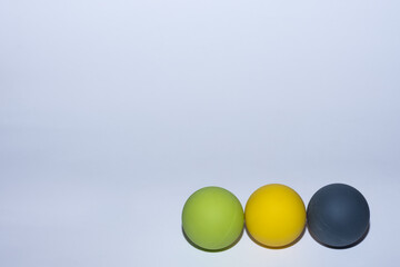 three different colored balls for massage in a row on gray background right