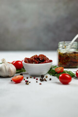 Sun dried tomatoes with fresh herbs, spices, tomatoes and garlik. Grey background.