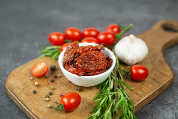 Sun dried tomatoes with fresh herbs, spices, tjmatoes and garlik. Grey background.