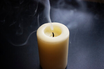 Photo of smouldering white candle on black background