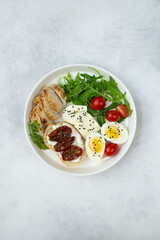 balanced breakfast with boiled eggs,  sandwiches with cream cheese, sun dried tomatoes,  green and vegetables