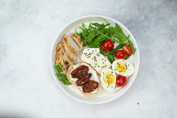 balanced breakfast with boiled eggs,  sandwiches with cream cheese, sun dried tomatoes,  green and vegetables