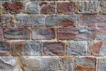 Texture of an antique facade of carved stone with different tones and colors.
