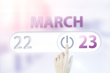 March 23rd. Day 23 of month, Calendar date.Hand finger switches pointing calendar date on sunlight office background. Spring month, day of the year concept.