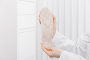 Doctor holding orthopedic insoles in his hands. Orthopedist tests the medical device. Orthopedic...