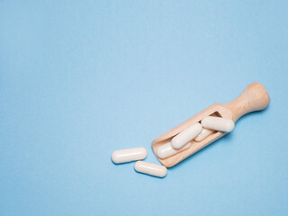 White tablets or capsules lie in a wooden spoon: the medical concept of dose selection for patients when prescribing treatment