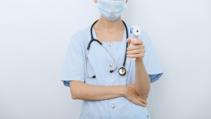Temperature measurement gun in doctor hands. Close-up shot of doctor wearing protective surgical...