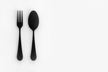 Spoon and fork are black on gray background. Isolated items. flat lay. Horizontal image. 3D image. 3D rendering.