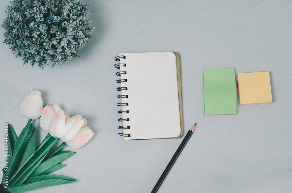 Poster top view blank notepad flower and pencil on desk. flat lay with copy space of table office.