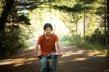 happy teen boy riding a bike on natural background, forest or park. healthy lifestyle, family day out