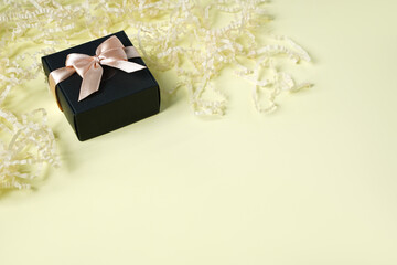 Obraz na płótnie Canvas Dark gift present box with ribbon and bow on yellow background top view copy space. Flat lay holiday background. Birthday present, March 8, Mother's Day, Valentine's Day. Congratulation for men