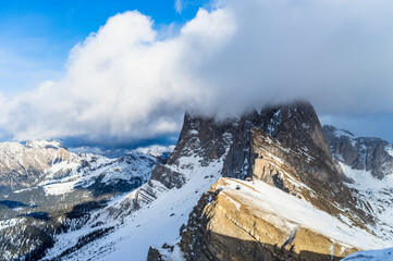 Seceda peak between clouds and snow in winter, Dolomites Alps, Italy
