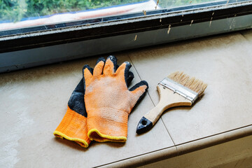 Construction gloves and a paint brush are on the windowsill. Interior decoration of the premises....